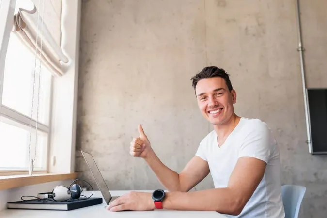 Young Handsome Smiling Man Casual Outfit Sitting Table Working Laptop Freelancer Home X - Certified Computer-Aided Design Specialist study guide