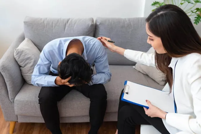 Stressed Asian Young Man Patient Have Life Problem Sitting Sofa With Hands Holding His Head While Woman Psychiatrist Trying Console Him 1 X - American Association of Suicidology Certification study guide