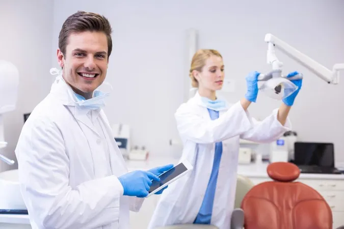 Dentist Using Digital Tablet While His Colleague Adjusting Dental Light X - American Board of Periodontology study guide