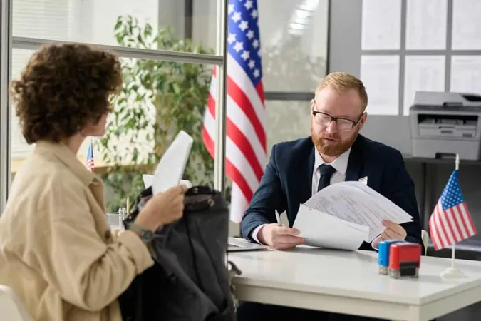 Portrait Male Worker Revising Documents Young Woman Applying Visa Us Immigration Office X - American Payroll Association Certification study guide