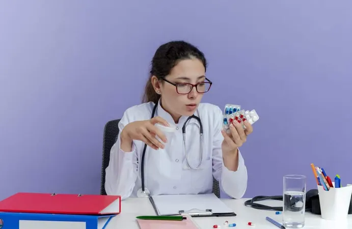 Impressed Young Female Doctor Wearing Medical Robe Stethoscope Sitting Desk With Medical Tools Holding Looking Medical Pills Holding Beaker Isolated X - Australian Pharmacy Council study guide