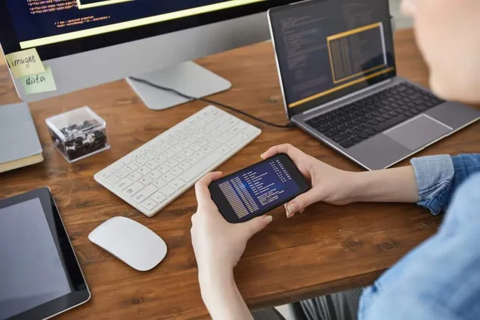 High Angle Closeup Female Hands Holding Smartphone With Code Screen While Working Desk Office Female It Developer Concept Copy Space X - Certified Application Developer study guide