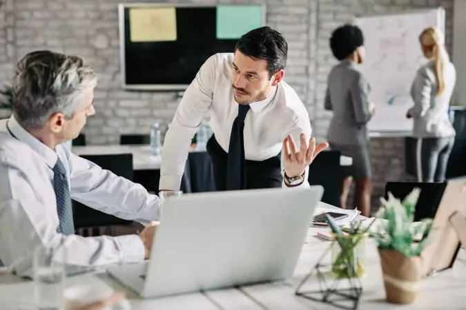 Young Serious Businessman Talking His Male Colleague Office There Are People Working Background X - Certified Conflict Manager study guide