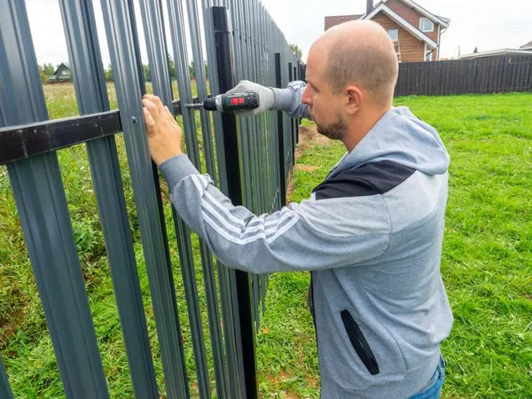Man Using Screwdriver Twists Metal Picket Fence Fence Worker Professional Construction Fencing Security Own Territory X - Certified Fence Professional study guide