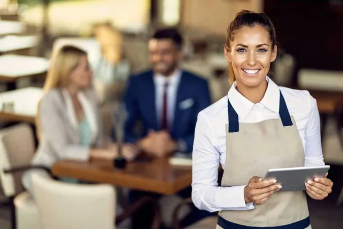 Young Happy Waitress Using Touchpad While Working Cafe X - Certified Hospitality Professional study guide