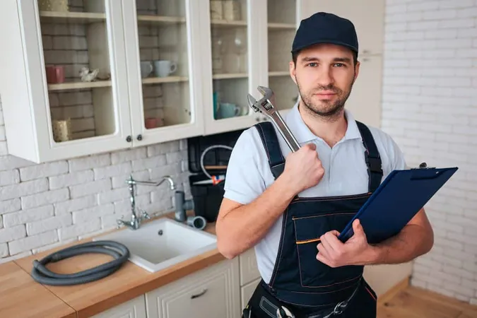 Handsome Young Man Kitchen Holding Wrench X - Certified Plumbing Designer study guide