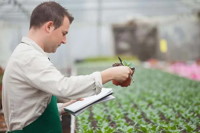 Man Standing Greenhouse Taking Notes X - Certified Plant Manager study guide