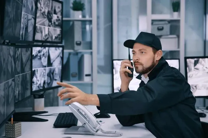 Male Security Guard Using Radio Transmitter Surveillance Room X - Certified Security Investigator study guide