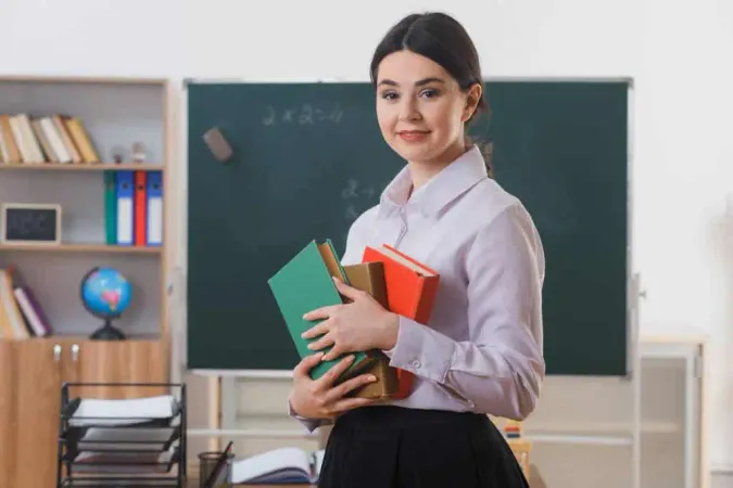 Smiling Holding Books Young Teacher Standing Front Blackboard Classroom - Georgia Professional Standards Commission - Professional Educator Certificate study guide