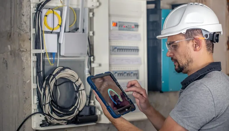 Man Electrical Technician Working Switchboard With Fuses Uses Tablet 1 X - Utility Management Certification study guide